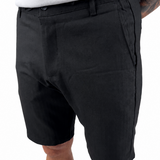 A person wearing black casual shorts with a white top, shown from the waist down against a plain white background.