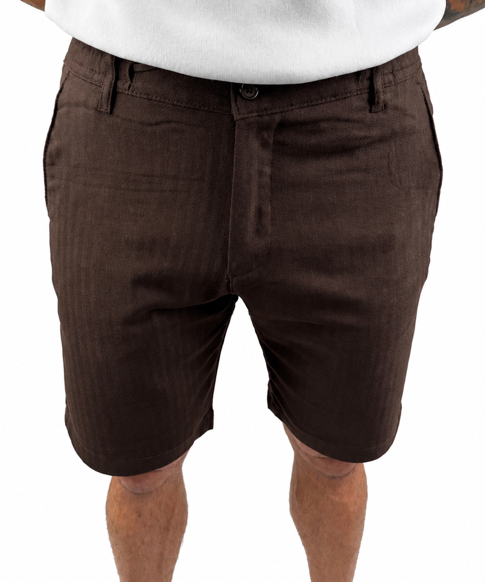 A person wearing dark brown chino shorts with a white t-shirt, cropped from the chest down, against a plain white background.