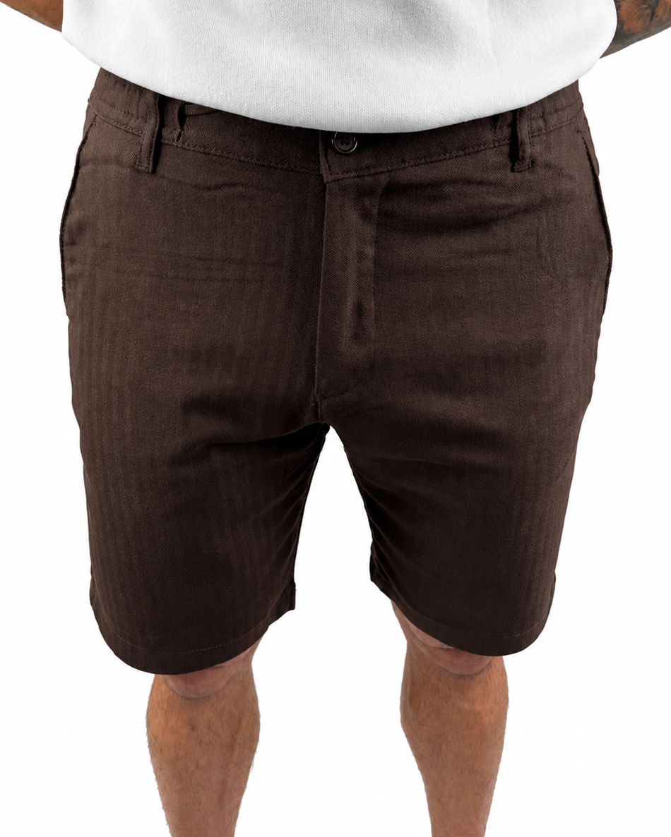 A person wearing dark brown chino shorts with a white t-shirt, cropped from the chest down, against a plain white background.