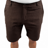 A person wearing dark brown chino shorts with a white t-shirt, cropped from the chest down, against a plain white background.