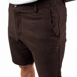 A person wearing dark brown linen shorts and a white tank top, shown from the chest down against a plain white background.