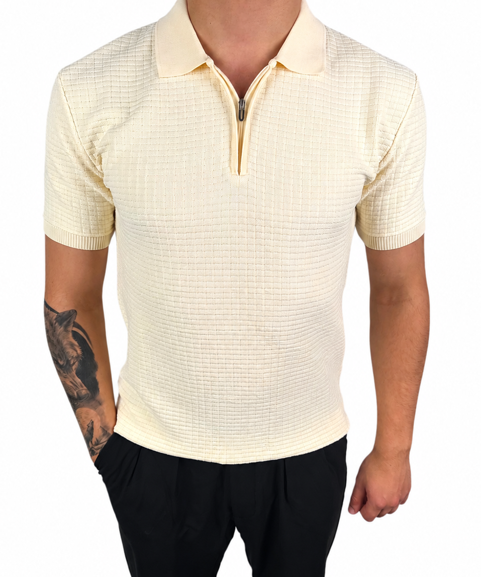 A man wearing a short-sleeve polo shirt with a subtle grid texture in cream or pale yellow, paired with black pants, shown against a plain white background.