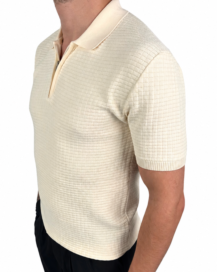 A man wearing a short-sleeve knit polo shirt in cream with a subtle grid texture, paired with black pants, shown from a side profile against a white background.