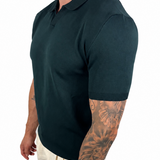 A man wearing a dark green short-sleeve polo shirt and off-white trousers, shown from a side profile against a plain white background.