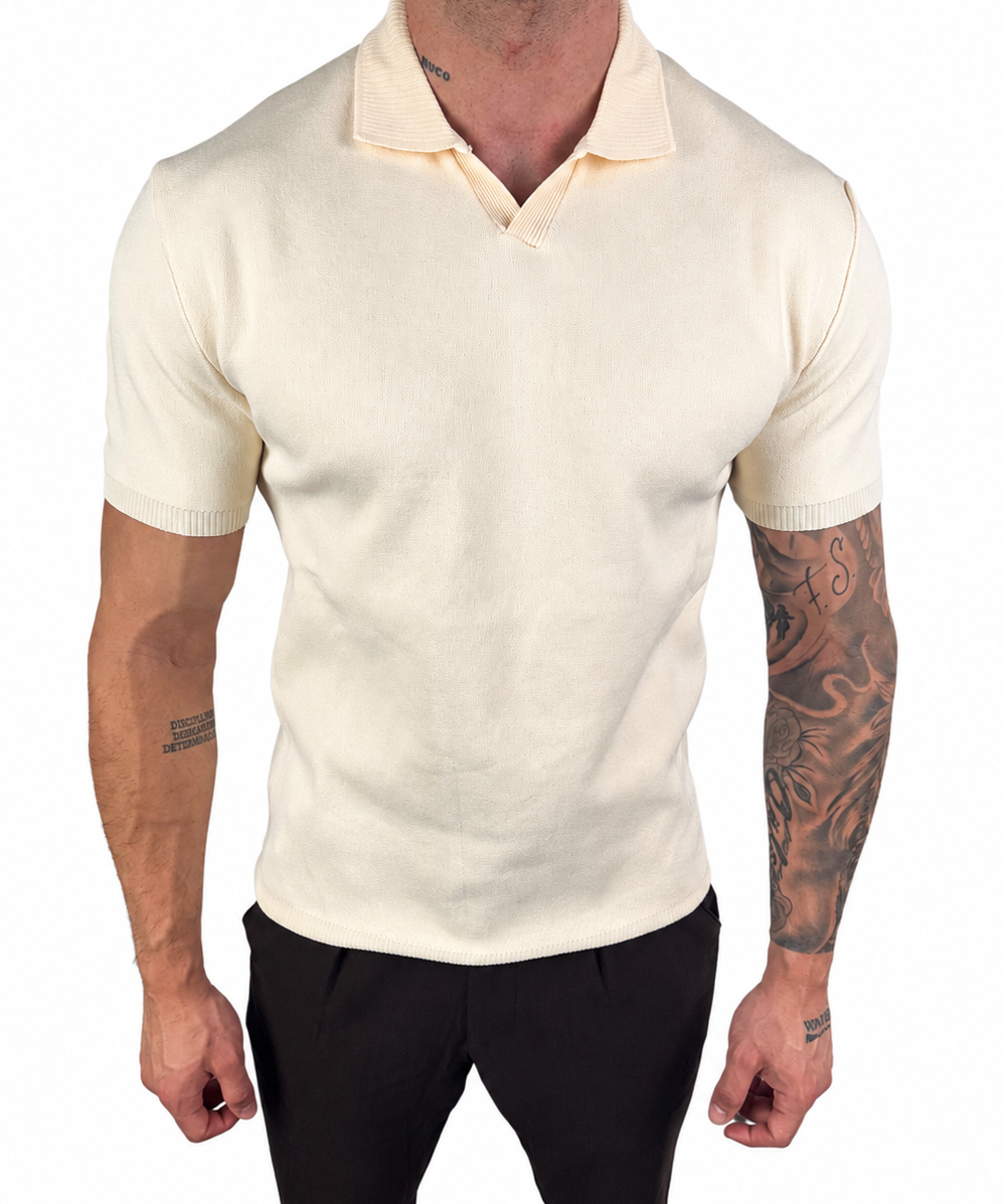 A man wearing a fitted short-sleeve knit polo shirt in cream or off-white, paired with black pants, shown against a plain white background.