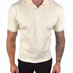 A man wearing a fitted short-sleeve knit polo shirt in cream or off-white, paired with black pants, shown against a plain white background.