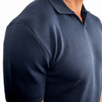 A close-up side view of a man wearing a dark navy blue short-sleeve knit polo shirt against a plain white background.