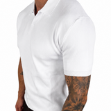 A man wearing a white short-sleeve polo shirt and black pants, shown from the side against a plain white background.