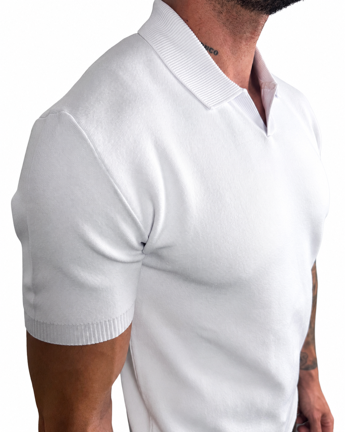 A close-up of a man wearing a white short-sleeve knit polo shirt, showing the ribbed collar, sleeve cuffs, and fitted texture against a plain white background.