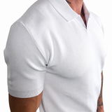 A close-up of a man wearing a white short-sleeve knit polo shirt, showing the ribbed collar, sleeve cuffs, and fitted texture against a plain white background.