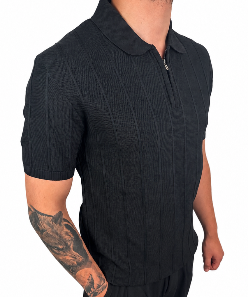 A man wearing a black short-sleeve polo shirt with vertical textured stripes and matching black pants, shown from the neck down against a plain white background.