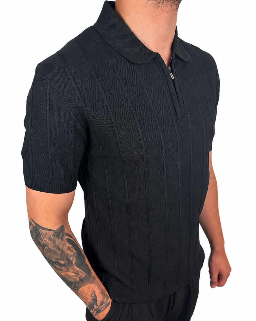 A man wearing a black short-sleeve polo shirt with vertical textured stripes and matching black pants, shown from the neck down against a plain white background.