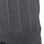 Close-up of a person wearing a dark gray ribbed knit top and dark gray pants, with the hand resting near the pocket, against a plain white background.