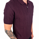 A man wearing a short-sleeve ribbed knit polo shirt in deep burgundy, paired with black trousers, shown from the waist up against a plain white background.