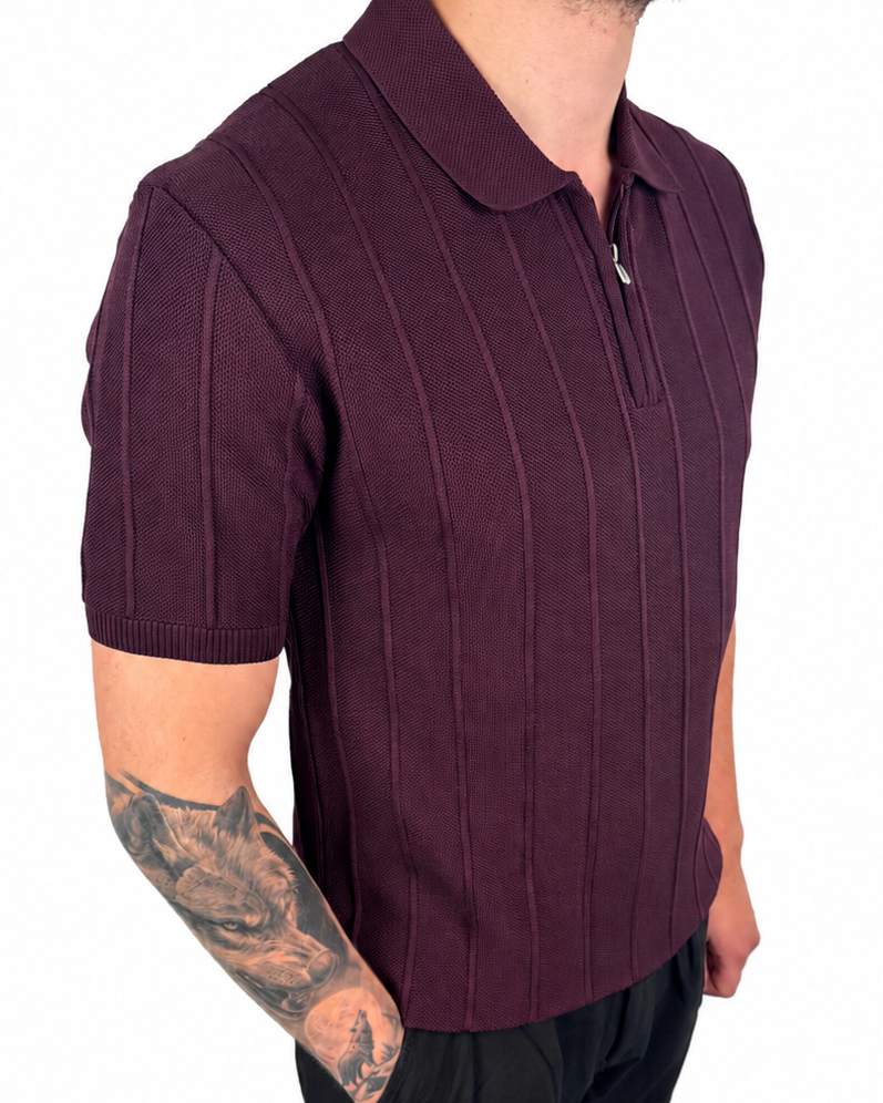 A man wearing a short-sleeve ribbed knit polo shirt in deep burgundy, paired with black trousers, shown from the waist up against a plain white background.