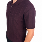 A man wearing a short-sleeve polo shirt in a deep plum purple color with vertical textured stripes, paired with black pants, shown from a side profile against a white background.