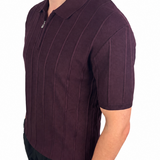 A man wearing a short-sleeve polo shirt in a deep plum purple color with vertical textured stripes, paired with black pants, shown from a side profile against a white background.