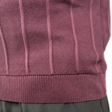 Close-up of a person wearing a ribbed knit sweater vest in a muted mauve-purple color, paired with dark gray trousers, against a plain white background.