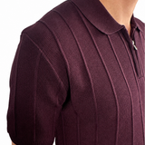 Close-up of a man wearing a short-sleeve polo shirt in deep burgundy with a textured knit pattern and a partial zip collar, shown against a plain white background.