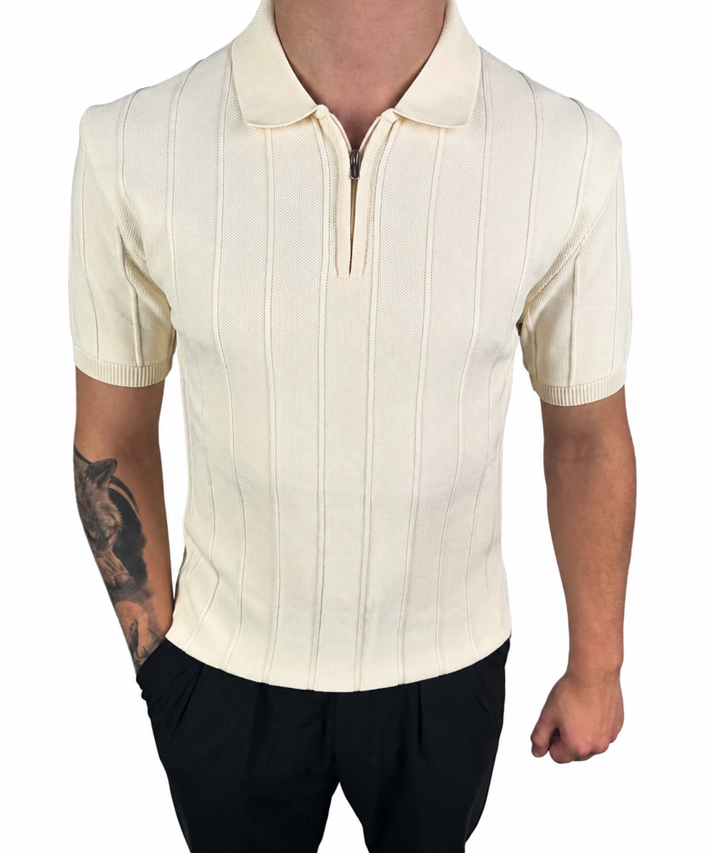 A man wearing a cream-colored short-sleeve polo shirt with vertical ribbed stripes and a half-zip collar, paired with black pants, shown against a plain white background.