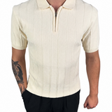 A man wearing a cream-colored short-sleeve polo shirt with vertical ribbed stripes and a half-zip collar, paired with black pants, shown against a plain white background.