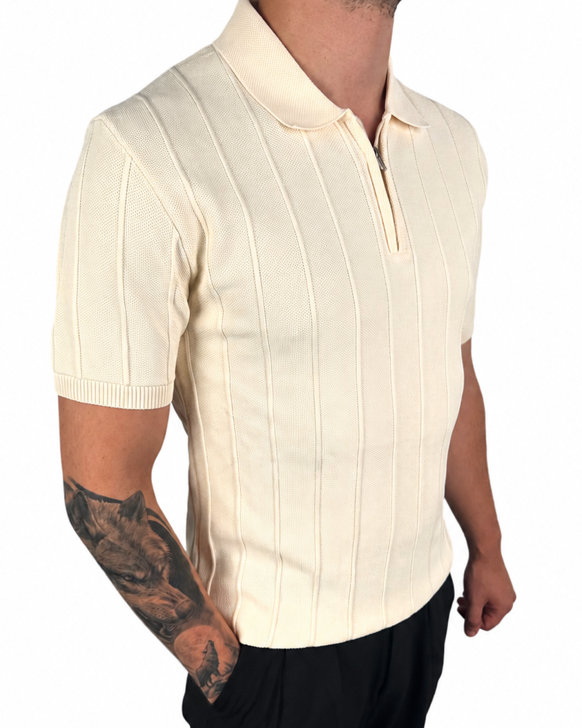 A man wearing a cream-colored short-sleeve knit polo shirt with vertical ribbed stripes and a half-zip collar, paired with black pants, shown against a plain white background.