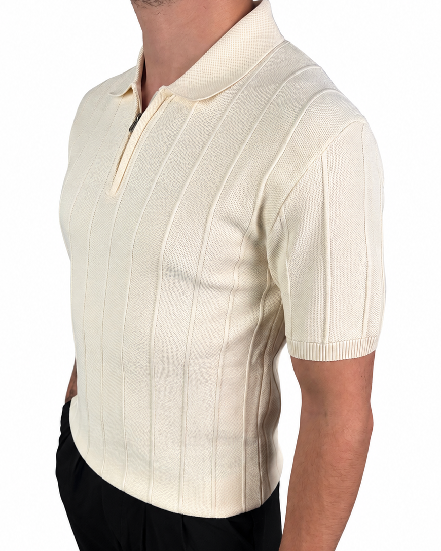 A man wearing a cream-colored short-sleeve knit polo shirt with vertical ribbed stripes and a half-zip collar, paired with black trousers, shown from a side profile against a white background.