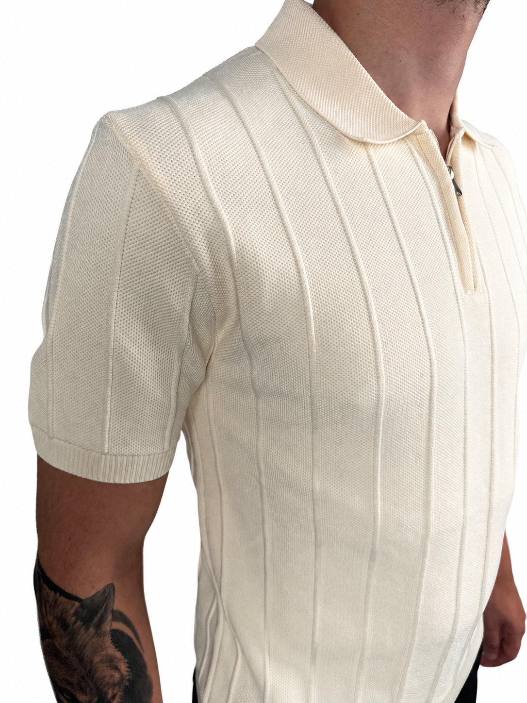 A close-up of a man wearing a cream-colored short-sleeve knit polo shirt with vertical ribbed stripes and a half-zip collar.