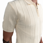 A close-up of a man wearing a cream-colored short-sleeve knit polo shirt with vertical ribbed stripes and a half-zip collar.