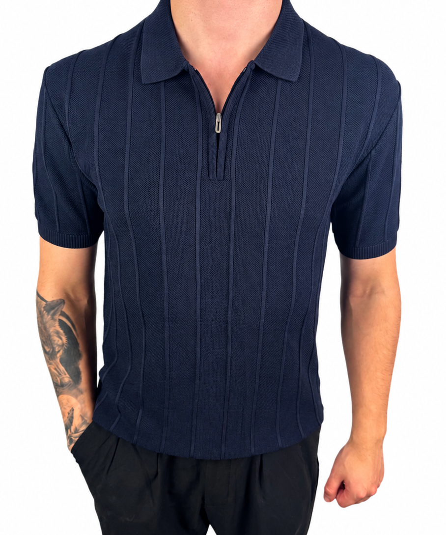 A man wearing a navy blue short-sleeve polo shirt with a vertical textured stripe pattern and a half-zip collar, paired with black pants, shown against a plain white background.