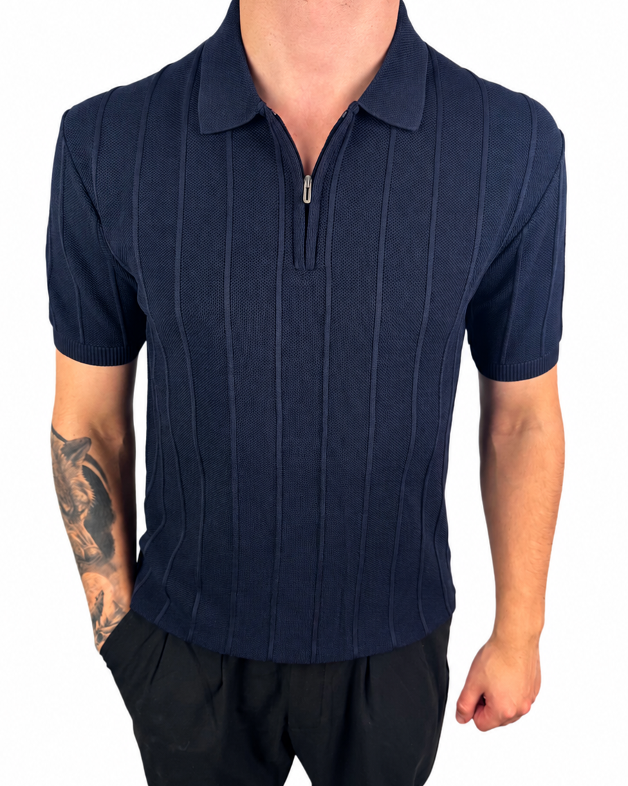 A man wearing a navy blue short-sleeve polo shirt with a vertical textured stripe pattern and a half-zip collar, paired with black pants, shown against a plain white background.