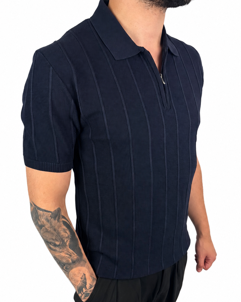 A man wearing a dark navy blue short-sleeve polo shirt with thin vertical pinstripes and a half-zip collar, paired with black pants, shown against a plain white background.
