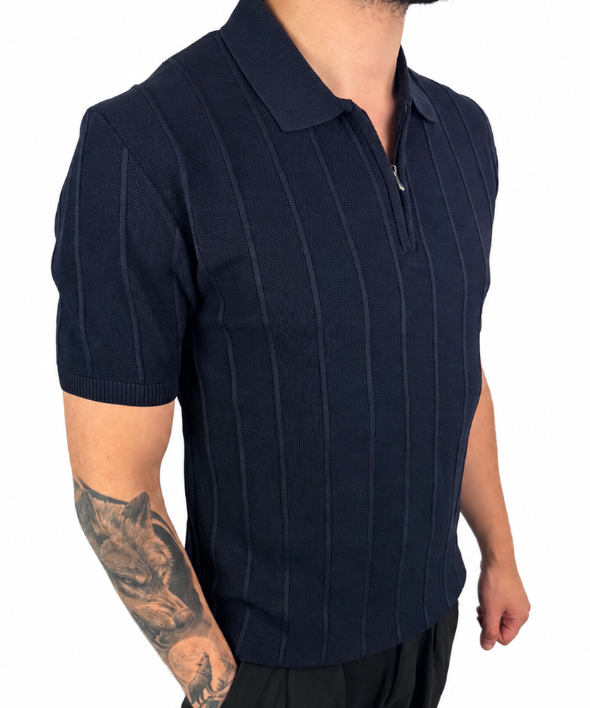 A man wearing a dark navy blue short-sleeve polo shirt with thin vertical pinstripes and a half-zip collar, paired with black pants, shown against a plain white background.