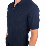 A man wearing a navy blue short-sleeve polo shirt with thin vertical pinstripes and a half-zip collar, paired with black pants, shown against a plain white background.