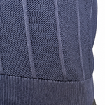 Close-up of a person wearing a navy ribbed knit top and dark pants, with the hand and arm visible against a plain white background.