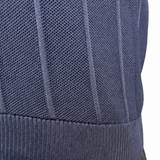 Close-up of a person wearing a navy ribbed knit top and dark pants, with the hand and arm visible against a plain white background.