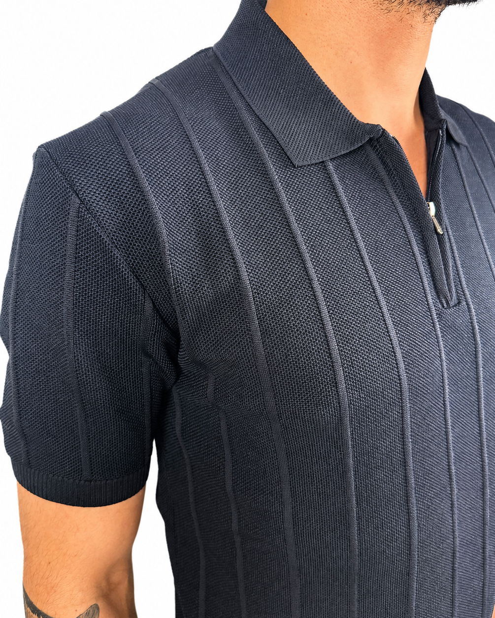 A close-up of a man wearing a dark navy blue short-sleeve polo shirt with vertical textured stripes and a half-zip collar.