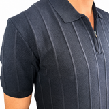 A close-up of a man wearing a dark navy blue short-sleeve polo shirt with vertical textured stripes and a half-zip collar.