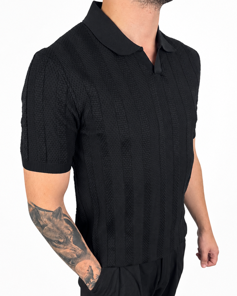 A man wearing a black short-sleeve polo shirt with a textured knit pattern and black pants, shown from the neck down against a plain white background.