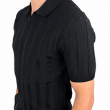 A man wearing a black short-sleeve polo shirt with a textured vertical knit pattern, shown from a side profile against a plain white background.