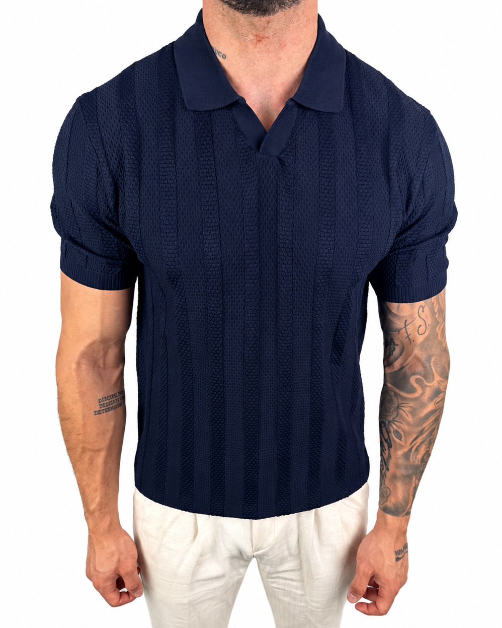 A man wearing a navy blue short-sleeve polo shirt with a textured knit pattern and white pants, shown from the neck down against a plain white background.