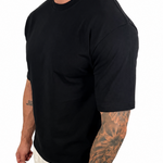 A man wearing a plain black short-sleeve crewneck t-shirt and light beige pants, shown from a side/back angle against a solid white background.