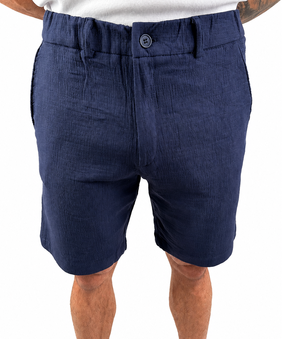 A person wearing navy blue textured shorts, shown from the waist down against a plain white background.