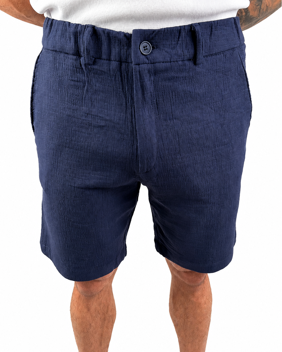 A person wearing navy blue textured shorts, shown from the waist down against a plain white background.