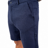 A man wearing navy blue textured shorts and a white t-shirt, shown from the waist down against a plain white background.