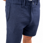 A close-up of a person wearing navy blue textured shorts with a white shirt partially visible at the top, against a plain white background.