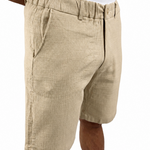 A person wearing beige textured linen shorts and a white tank top, shown from the chest down against a plain white background.